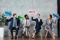 Happy multiethnic businesspeople holding speech bubbles with idea, success, planning and strategy lettering while sitting in