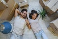 Happy multiethnic couple lying on floor after moving to a new home. Royalty Free Stock Photo