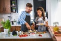 Happy multiethnic couple preparing home made tomato and basil pasta. Cooking at home