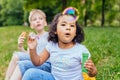 Happy multiethnic different age kids eating ice creams outdoor in summer. Cute positive hispanic girl enjoying blowing bulbs with Royalty Free Stock Photo