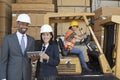 Happy multiethnic engineers holding tablet PC with female worker driving forklift truck in background Royalty Free Stock Photo