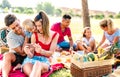 Happy multiethnic families playing with phone at pic nic garden party - Joy and love life style concept with mixed race people Royalty Free Stock Photo