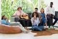 Group of diverse friends sitting on couch and enjoy drinking in living room while having party at home. Cheerful African woman Royalty Free Stock Photo