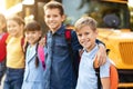 Happy multiethnic group of kids posing outside by yellow school bus Royalty Free Stock Photo