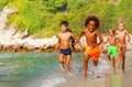 Happy multiethnic kids running along sandy beach Royalty Free Stock Photo