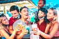 Happy multiethnic people drinking at night bar with open face masks - New normal summer concept with millenial friends having fun Royalty Free Stock Photo