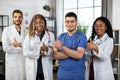 Happy multiethnic team of four healthcare practitioners, showing thumbs up at hospital room