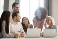 Smiling diverse employees laugh working together at laptop in office Royalty Free Stock Photo