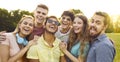 Happy multiethnic young friends taking selfie portrait while walking in summer park. Royalty Free Stock Photo