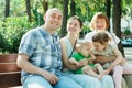 Happy multigeneration family of five sitting on bench