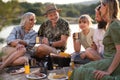 Happy multigeneration family on summer holiday trip, barbecue by lake.