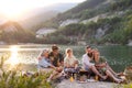 Happy multigeneration family on summer holiday trip, barbecue by lake at sunset. Royalty Free Stock Photo