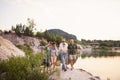Happy multigeneration family on summer holiday, walking by lake.