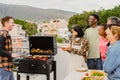 Happy multigenerational people having fun doing barbecue grill at house rooftop