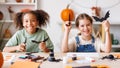 Happy multinational children girls making Halloween home decorations together