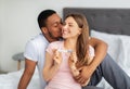 Happy multinational couple celebrating positive result of pregnancy test on bed at home Royalty Free Stock Photo