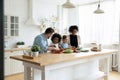 Happy multinational family with kids prepare vegetable salad in kitchen