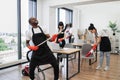 Happy multinational team of people in black aprons cleaning modern office.