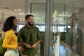 Happy multiracial colleagues looking at strategy on glass wall while discussing at modern workplace Royalty Free Stock Photo