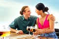 Happy multiracial couple on vacation having drinks together at a beach bar drinking beer. Royalty Free Stock Photo