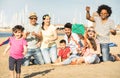 Happy multiracial families and children playing together with kite at beach vacation - Multicultural summer joy concept with Royalty Free Stock Photo