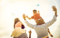 Happy multiracial families group with parents and children playing with kite at beach vacation - Summer joy concept