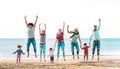 Happy multiracial families jumping together at beach holding hands - Summer vacation concept with young mixed race people having Royalty Free Stock Photo