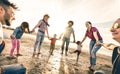 Happy multiracial families round dancing at the beach at sunset Royalty Free Stock Photo