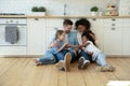 Happy multiracial family with children sitting on floor in kitchen Royalty Free Stock Photo