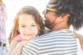 Happy multiracial family having fun on the beach - Young daughter hugging her father in summer vacation - Love, tender moments,