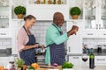 Happy multiracial senior couple dancing in kitchen while cooking food together at home Royalty Free Stock Photo