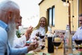 Happy multiracial senior friends having fun dining together on house patio Royalty Free Stock Photo