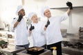 Happy multiracial team of cooks take selfie photo on phone while cooking together in the kitchen