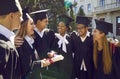 Happy multiracial university graduates walking, talking, laughing and hugging together outdoors. Royalty Free Stock Photo