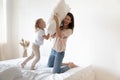 Happy mum and kid daughter play pillow fight on bed Royalty Free Stock Photo