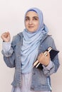 Happy Muslim businesswoman celebrating her first success in business. Attractive Muslim student holds notepads and celebrates
