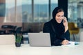 Happy muslim businesswoman in hijab at office workplace. Smiling Arabic woman working on laptop and talking on Royalty Free Stock Photo