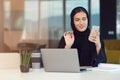 Happy muslim businesswoman in hijab at office workplace. Smiling Arabic woman working on laptop and talking on Royalty Free Stock Photo