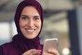 Happy muslim businesswoman in hijab at office workplace. Smiling Arabic woman working on laptop and using smatphone. Royalty Free Stock Photo