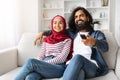 Happy Muslim Couple Watching Tv And Having Fun At Home Together Royalty Free Stock Photo