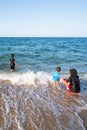 Muslim family playing in ocean surf on sunny summer