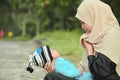 Happy muslim hijab mother holding a beautifull baby while her todler crying in the outdoor area Royalty Free Stock Photo