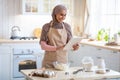 Happy Muslim Housewife In Hijab Using Digital Tablet In Kitchen While Baking
