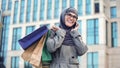 Happy Muslim lady chatting on phone outdoors shopping mall, black Friday sale