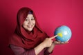 Happy muslim woman pointing earth globe map on her hand, geography study, global business or vacation plan concept Royalty Free Stock Photo