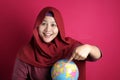 Happy muslim woman pointing earth globe map on her hand, geography study, global business or vacation plan concept Royalty Free Stock Photo