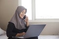 Happy Muslim Woman Working with Laptop and Smart Phone in Her Bedroom Royalty Free Stock Photo