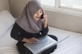 Happy Muslim Woman Working with Laptop and Smart Phone in Her Bedroom Royalty Free Stock Photo
