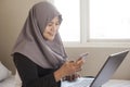 Happy Muslim Woman Working with Laptop and Smart Phone in Her Bedroom Royalty Free Stock Photo