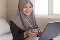 Happy Muslim Woman Working with Laptop and Smart Phone in Her Bedroom Royalty Free Stock Photo